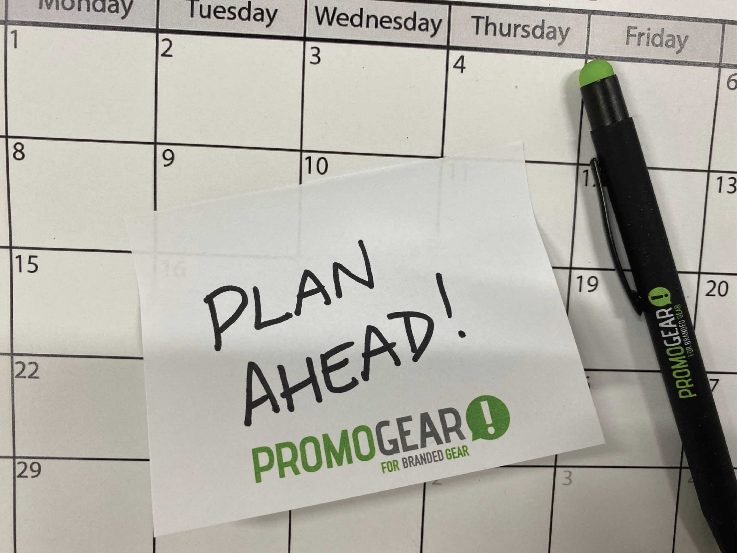 Start planning ahead now! Promo Gear branded sticky note and pen on a calendar