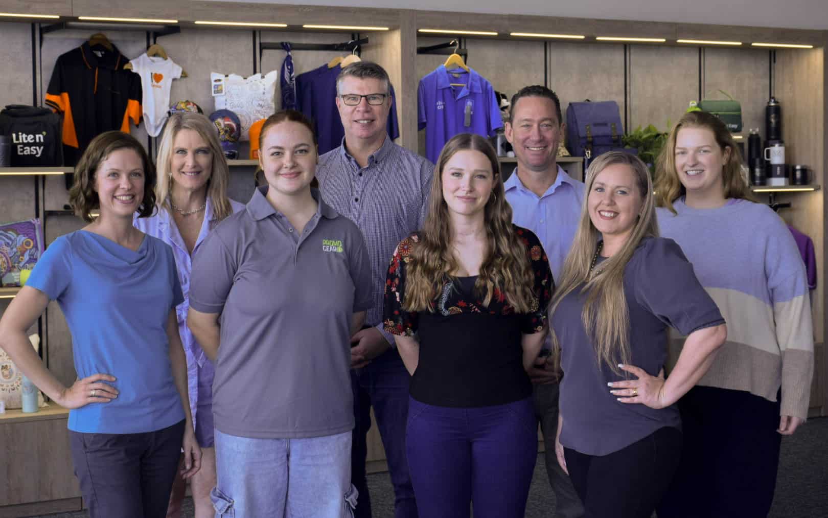 Promo Gear team posing of a photo with promotional products behind them